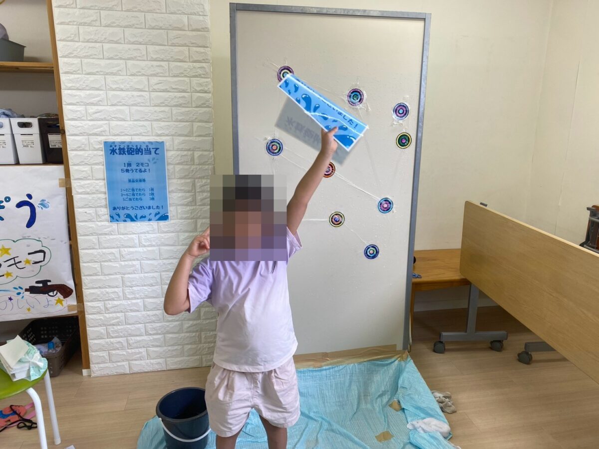 水鉄砲的当ての前でポーズをする子ども