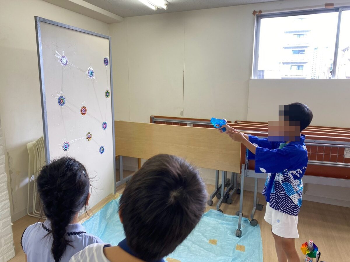水鉄砲で的をねらう子ども