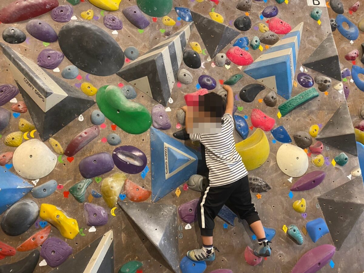 学童の夏休みイベントでボルダリングに挑戦する小学生