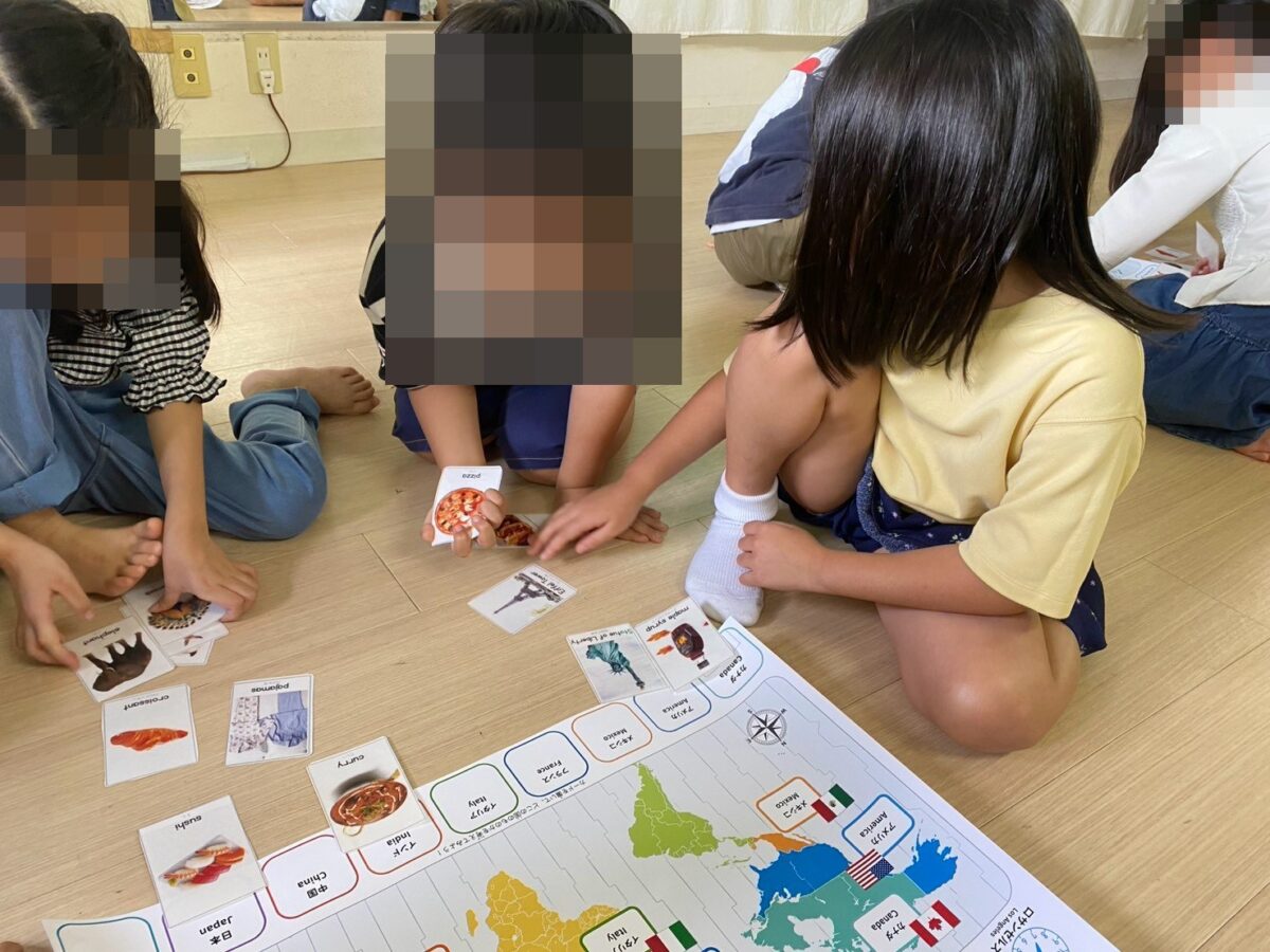 世界地図にカードを並べるマッピングゲームに取り組む子どもたち